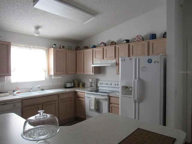 a kitchen with stainless steel appliances a sink a stove a refrigerator and cabinets
