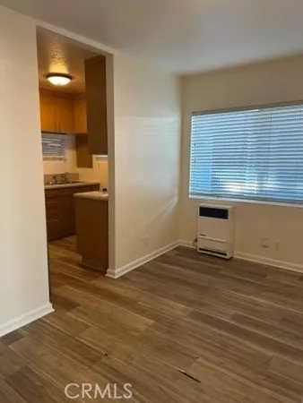 a view of kitchen and empty room with wooden floor
