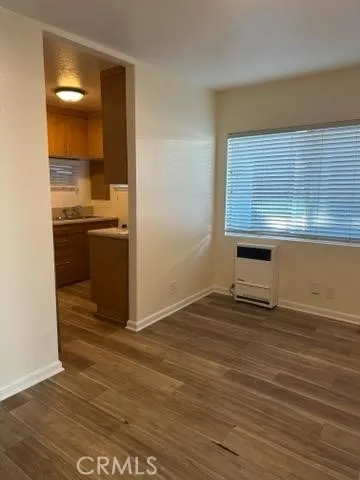 a view of kitchen and empty room with wooden floor