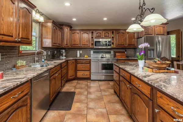 a large kitchen with stainless steel appliances granite countertop a sink counter space cabinets and a wooden floor