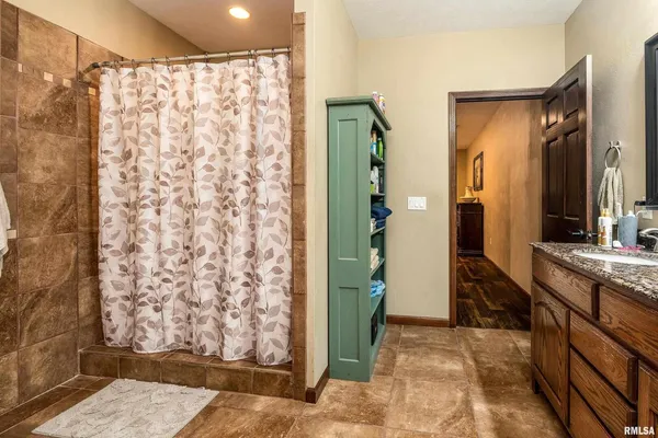 a bathroom with a granite countertop sink a mirror a shower and vanity