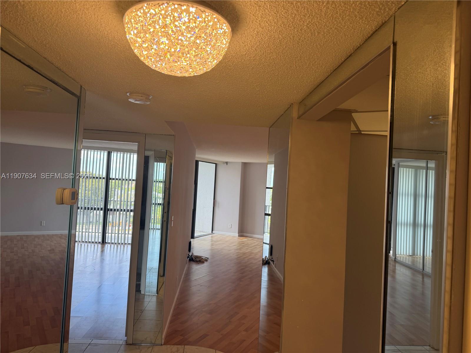 1000 Parkview Drive, Unit 511 Hallandale Beach, FL 33009 - Photo 12 of 17 a view of a hallway with wooden floor and a chandelier