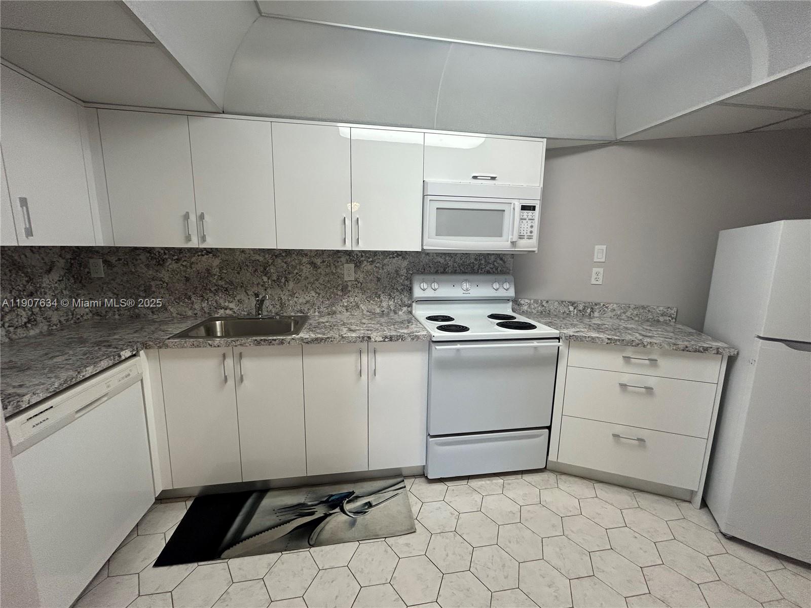 1000 Parkview Drive, Unit 511 Hallandale Beach, FL 33009 - Photo 2 of 17 a kitchen with white cabinets appliances and a sink