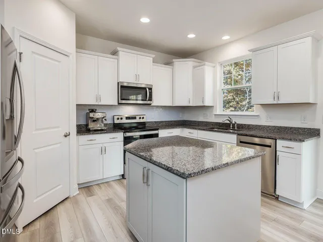 a kitchen with granite countertop white cabinets and a sink