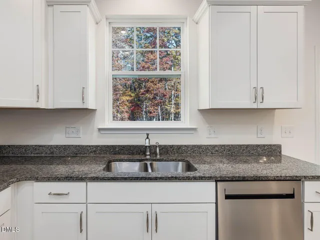 a kitchen with granite countertop a sink a counter top space and living room view