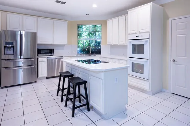 a kitchen with stainless steel appliances a sink a stove a refrigerator and island