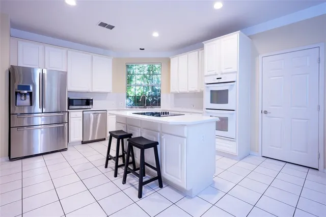 a kitchen with stainless steel appliances a sink a stove a refrigerator cabinets and a window