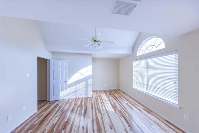 a view of empty room with wooden floor and fan