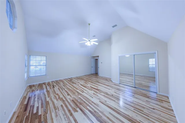 a view of empty room with wooden floor and fan