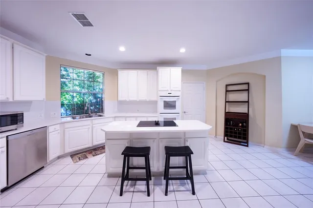 a kitchen with stainless steel appliances granite countertop a sink and dishwasher a oven with white cabinets
