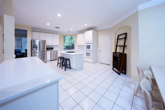 a living room with stainless steel appliances furniture a rug and a kitchen view