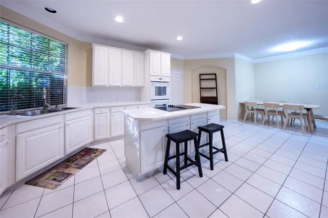 a kitchen with a sink white cabinets and glass table chairs