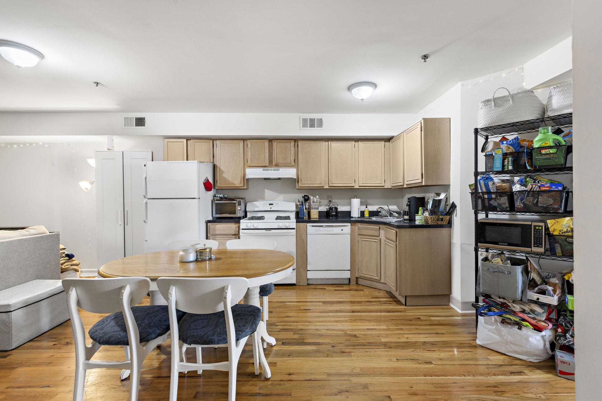 131 Clinton Street, Unit 1 Hoboken, NJ 07030 - Photo 8 of 13 a kitchen with a dining table chairs and refrigerator