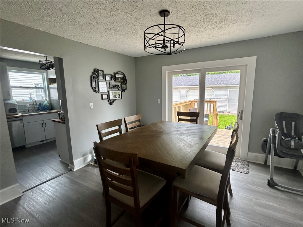 935 Lilly Road Alliance, OH 44601 - Photo 13 of 31 Dining area featuring a chandelier, healthy amount of natural light, a textured ceiling, and dark wood-style flooring