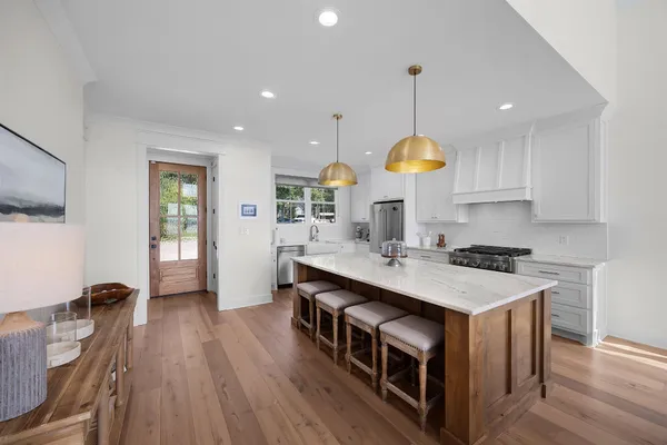 a kitchen with stainless steel appliances granite countertop a sink stove a refrigerator a kitchen island a stove and a wooden floors