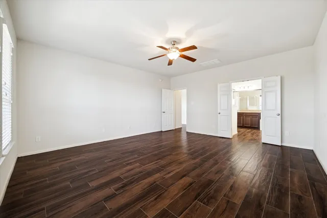 a view of empty room with wooden floor and fan