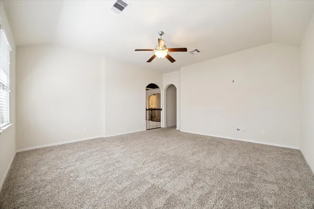 an empty room with chandelier fan and windows