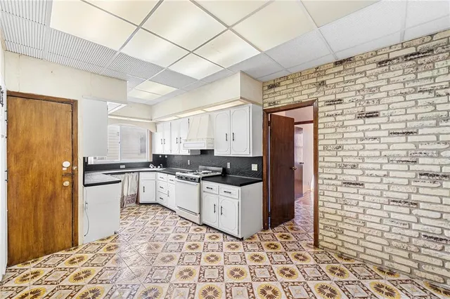 a kitchen with granite countertop a sink a stove and cabinets
