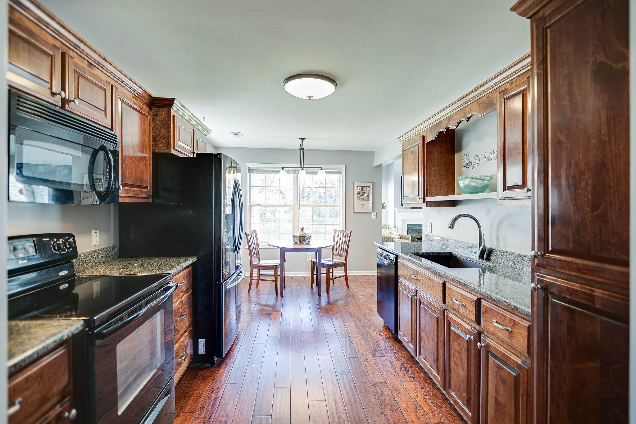 303 Cheairs Court Spring Hill, TN 37174 - Photo 6 of 23 a kitchen with stainless steel appliances granite countertop a stove top oven a sink dishwasher a refrigerator and a dining table with wooden floor