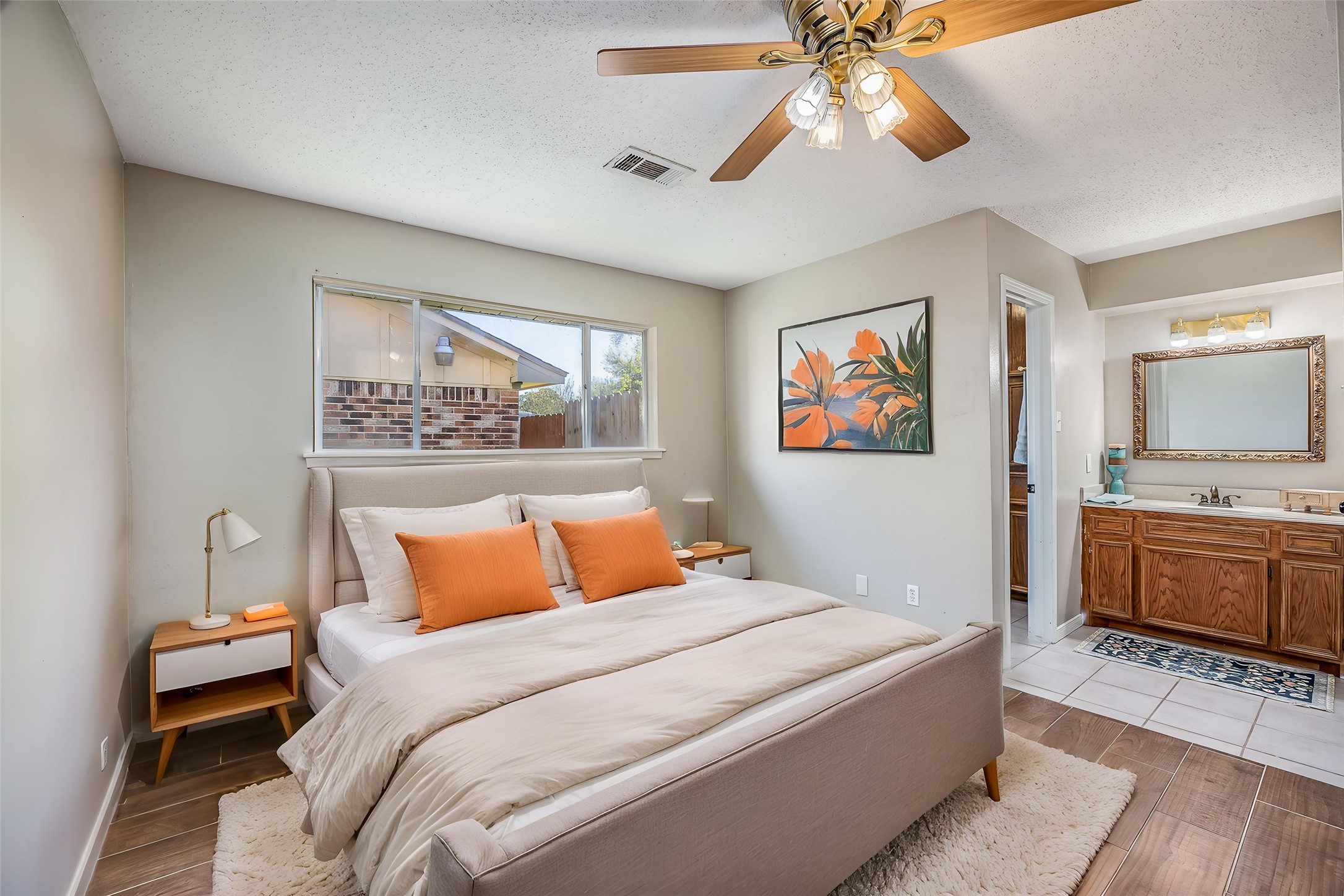 1603 East Baker Road Baytown, TX 77521 - Photo 16 of 26 Bright and cozy bedroom with neutral walls, featuring a ceiling fan and large window. An ensuite bathroom with a wooden vanity. Virtually staged.