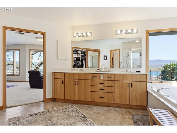 a bathroom with a tub a double vanity sink a vanity a window and a mirror