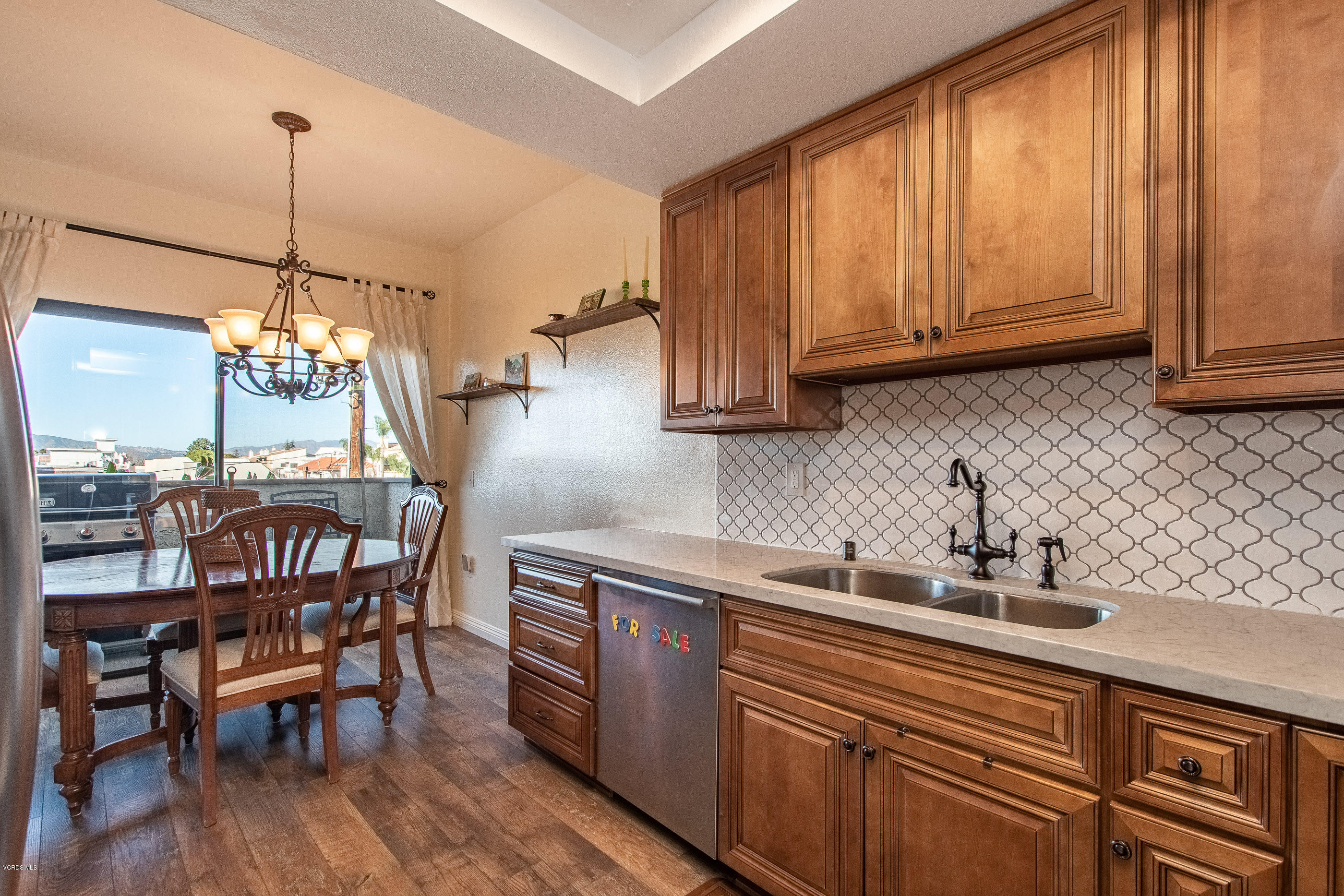 17914 West Magnolia Boulevard, Unit 316 Encino, CA 91316 - Photo 8 of 21 a kitchen with stainless steel appliances granite countertop wooden cabinets a dining table and chairs