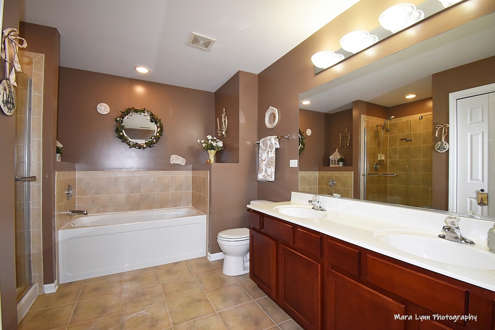 1986 West Cobblestone Road, Unit 1986 Romeoville, IL 60446 - Photo 24 of 36 a bathroom with a double vanity sink a toilet a mirror and shower