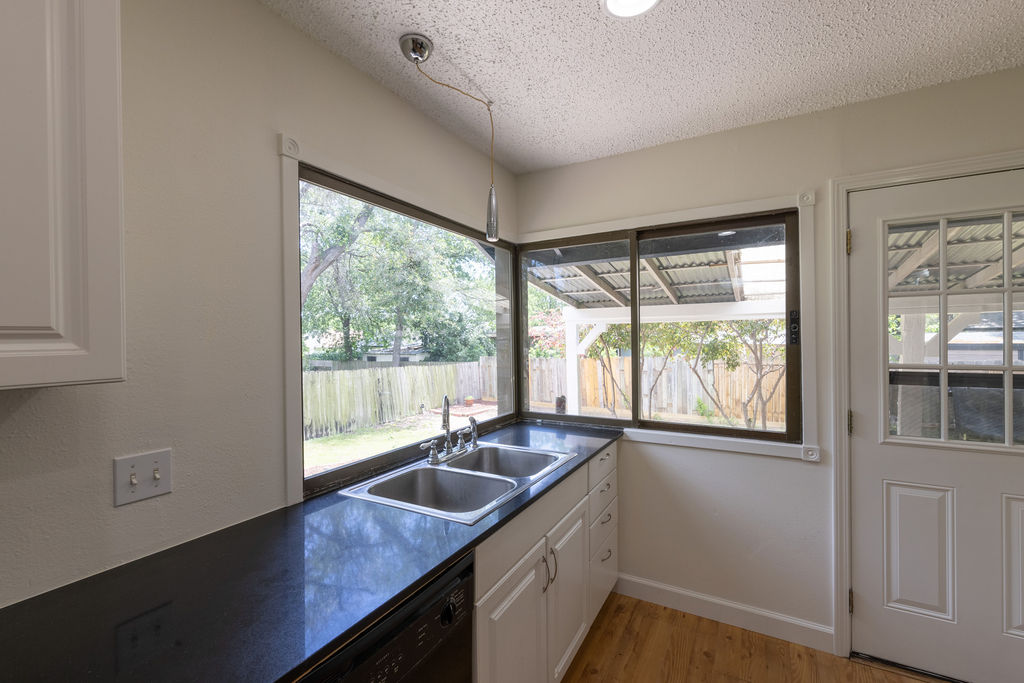 5310 Presidio Road Austin, TX 78745 - Photo 5 of 34 A well-lit kitchen with dual sinks offers serene views of the fenced yard through expansive windows.
