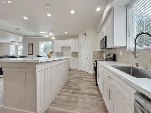 a large white kitchen with a large counter top cabinets and stainless steel appliances