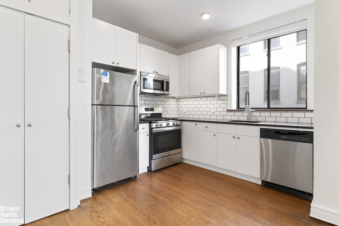 167 West 136th Street, Unit 4 Manhattan, NY 10030 - Photo 2 of 8 a kitchen with granite countertop white cabinets and white appliances