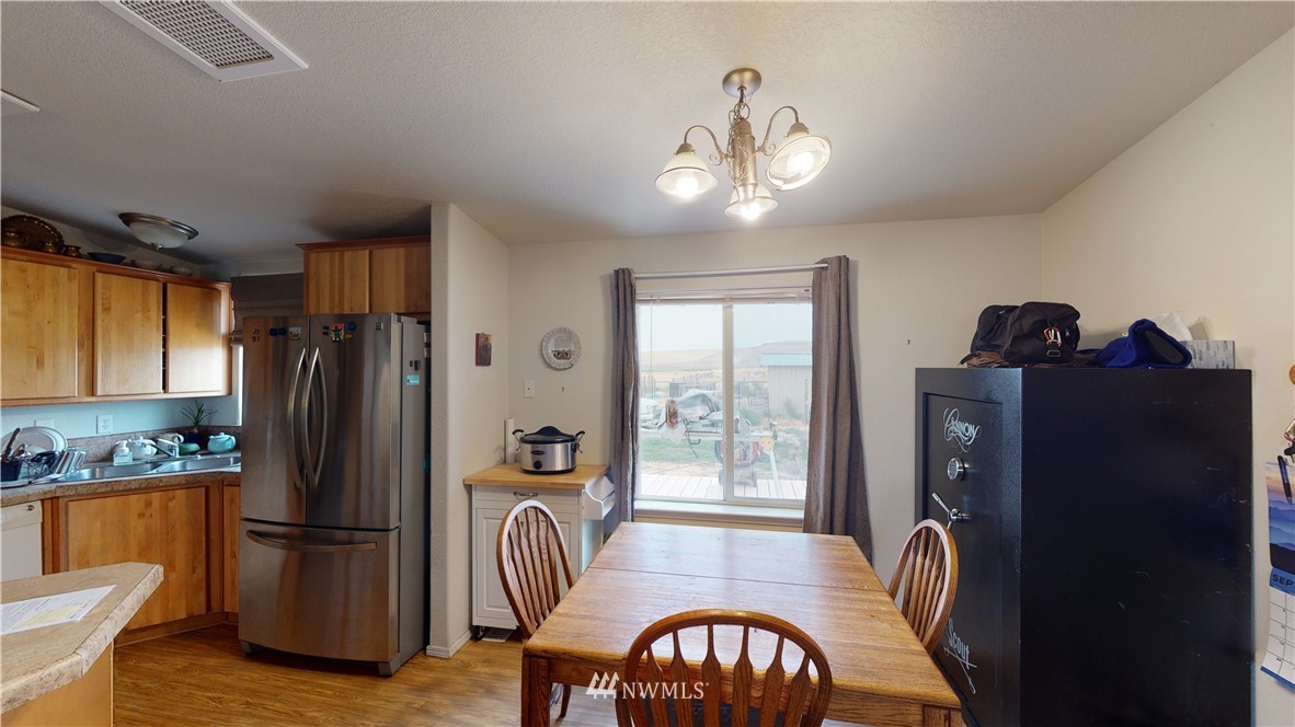 196 Skyrocket Road Prescott, WA 99348 - Photo 9 of 21 a kitchen with stainless steel appliances granite countertop a refrigerator a stove a sink a dining table and chairs with wooden floor