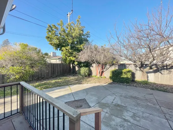 a view of a backyard with brick wall and potted plants