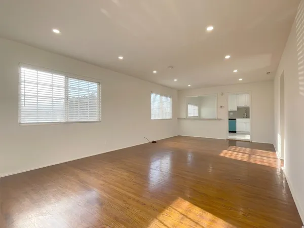 a view of an empty room with wooden floor and a window