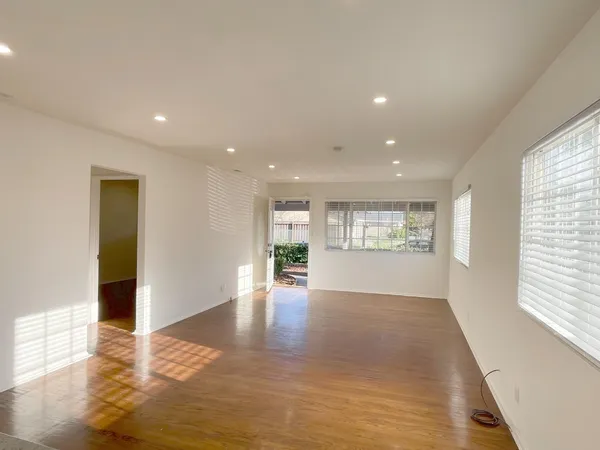 a view of an empty room with wooden floor and a window