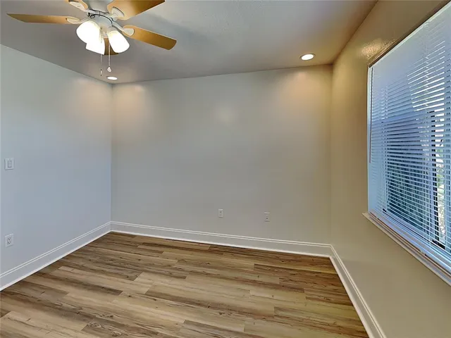 a view of an empty room with window and wooden floor