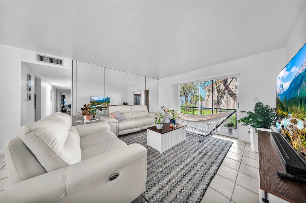 13700 Southwest 62nd Street, Unit 149 Miami, FL 33183 - Photo 12 of 16 a living room with furniture floor to ceiling window and a flat screen tv