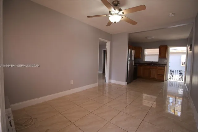 an empty room with chandelier fan and windows