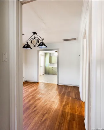 a view of a livingroom with wooden floor and a hallway