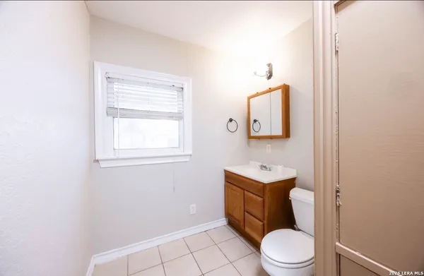 a bathroom with a toilet a sink a mirror and a window