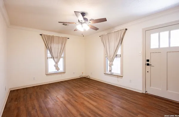 an empty room with wooden floor fan and windows