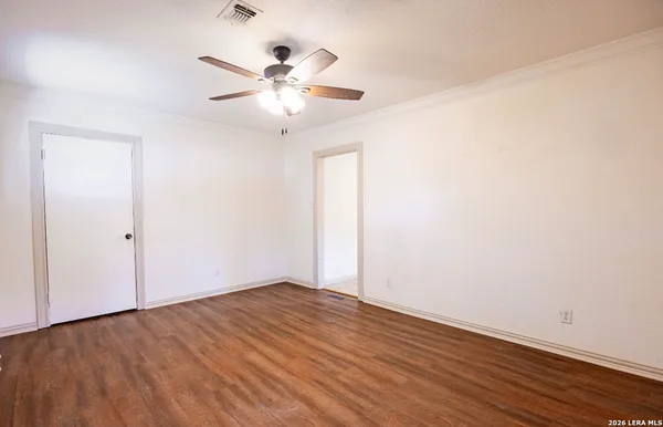 an empty room with wooden floor fan and windows