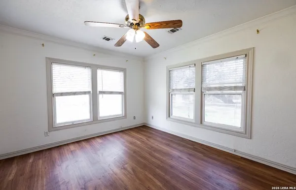 a view of an empty room with wooden floor and a window