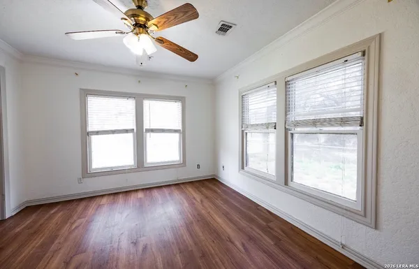 a view of an empty room with wooden floor and a window