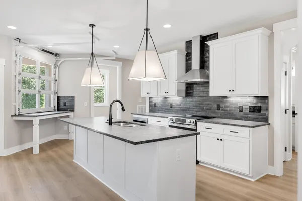 a kitchen with kitchen island granite countertop a sink a counter space appliances and a window
