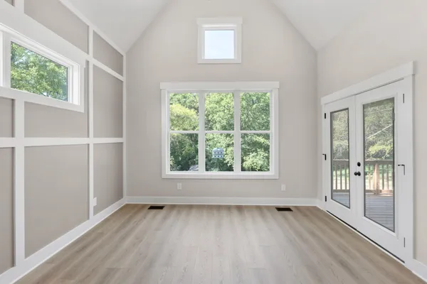 an empty room with wooden floor and windows