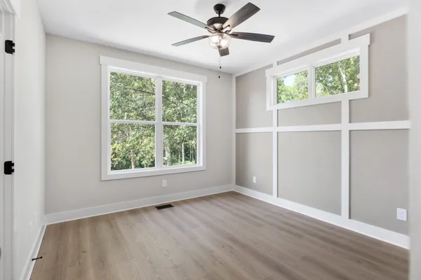 a view of an empty room with a window and wooden floor
