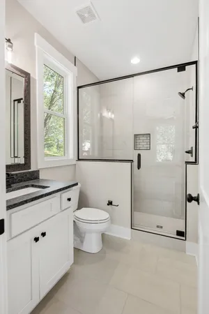 a bathroom with a granite countertop sink mirror vanity and toilet