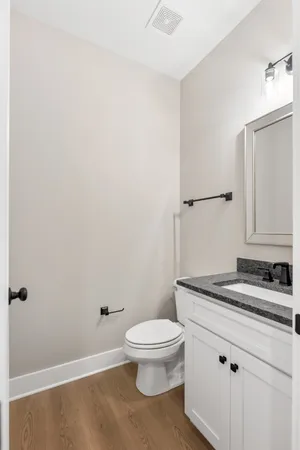 a bathroom with a granite countertop toilet and a sink