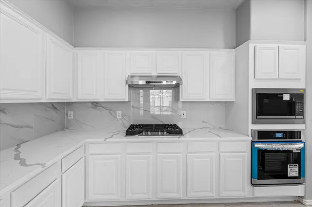 a kitchen with white cabinets and a stove top oven
