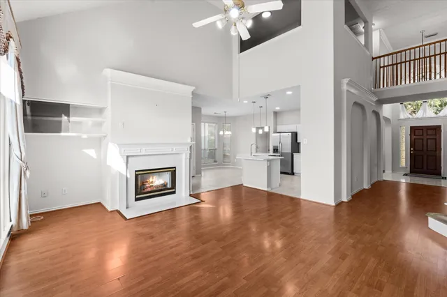 a view of a kitchen and an empty room with wooden floor and a kitchen